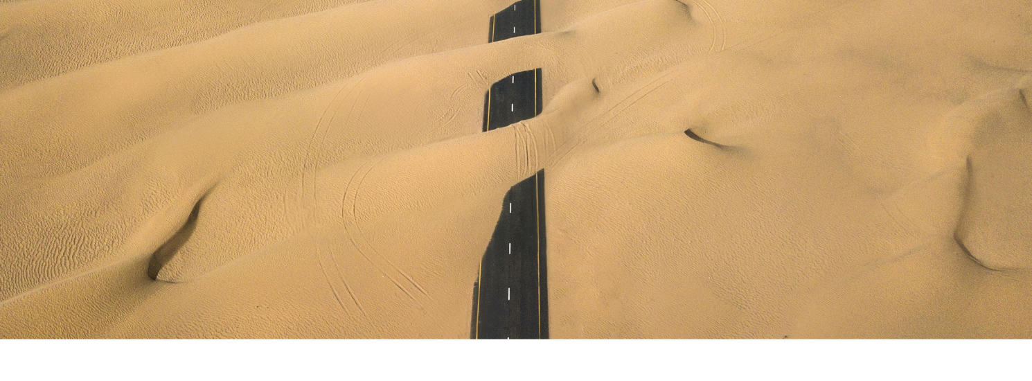 A road in the desert, partly covered in sand
