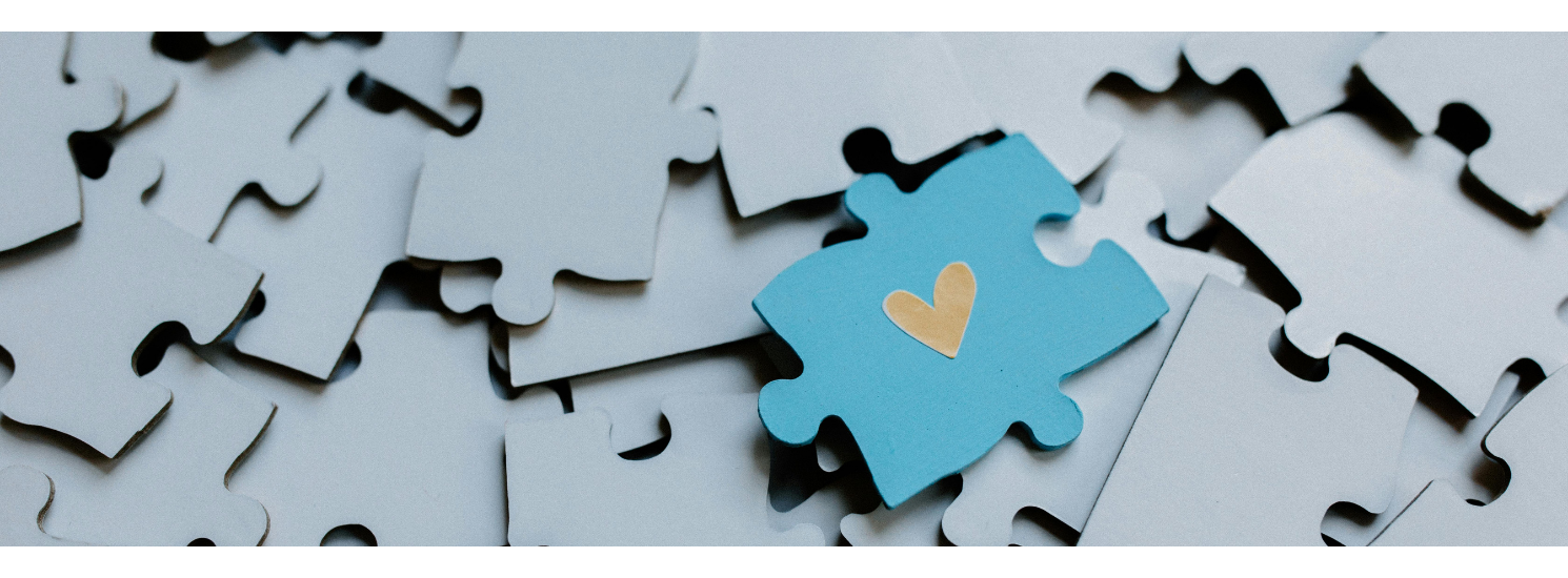 A pile of upside puzzle pieces, with one the right way up with a heart on it