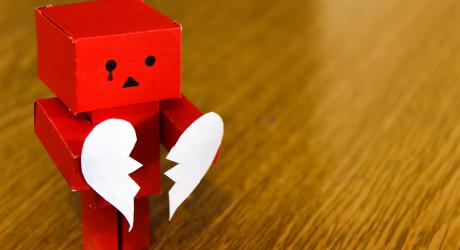 A paper robot holding a ripped paper heart