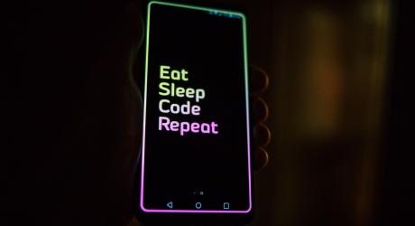 A phone showing the words "eat, sleep, code, repeat"