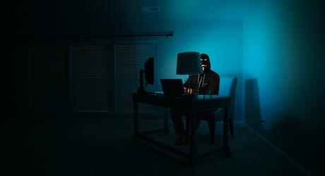 Person with an Anonymous mask using computer