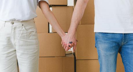 Two people holding hands in front of a stack of boxes