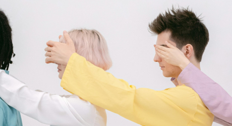 4 people in a line, each covering the eyes of the person in front