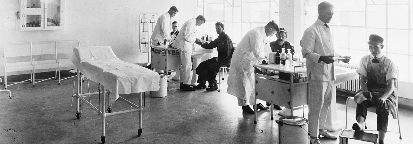 Temporary hospital unit with four heavily mustached doctors in white coats helping three scruffier looking men