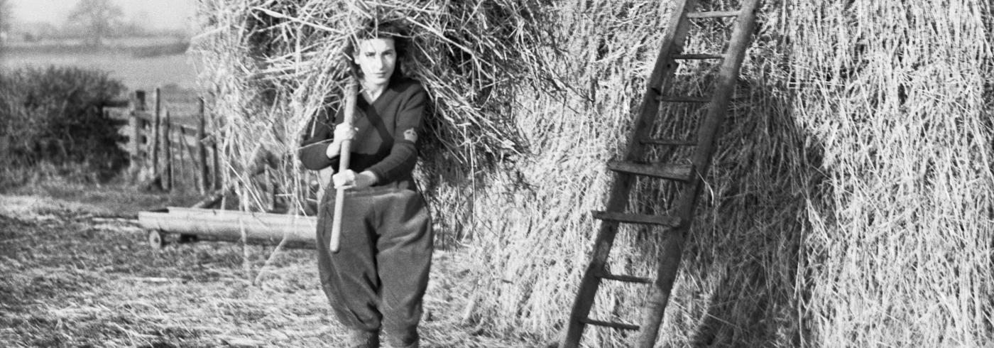 A girl carrying a fork full of hay