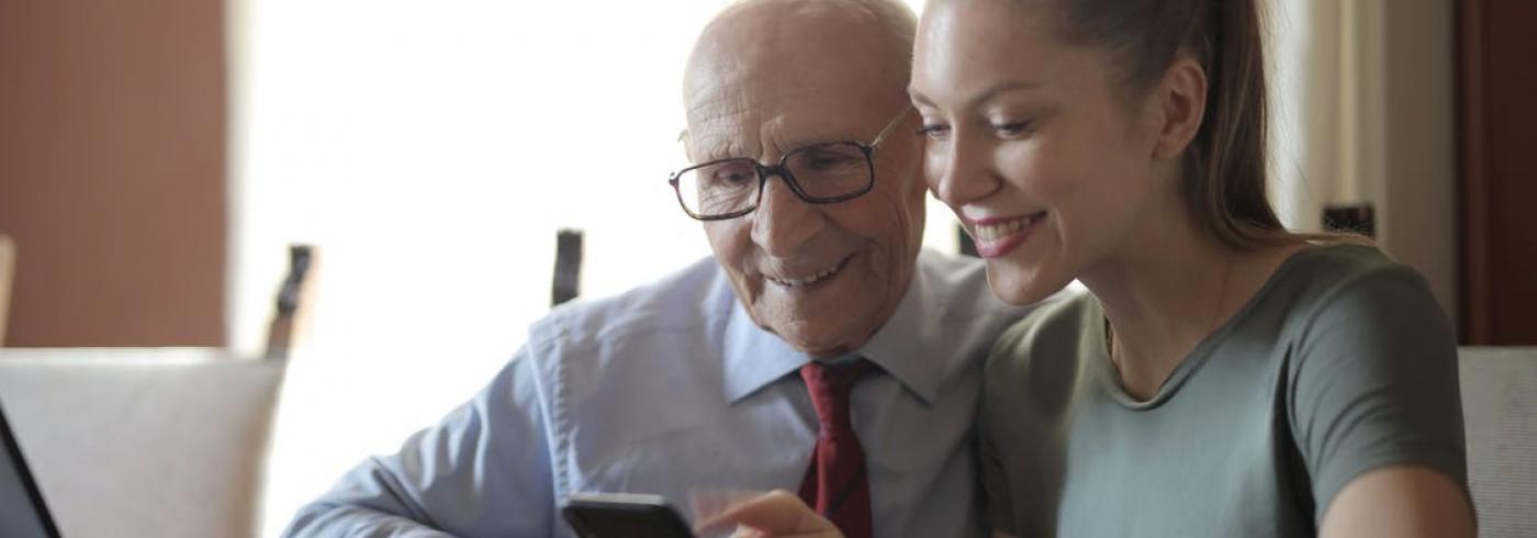 Older gentleman being shown how to use a smartphone by a younger lady.jpeg