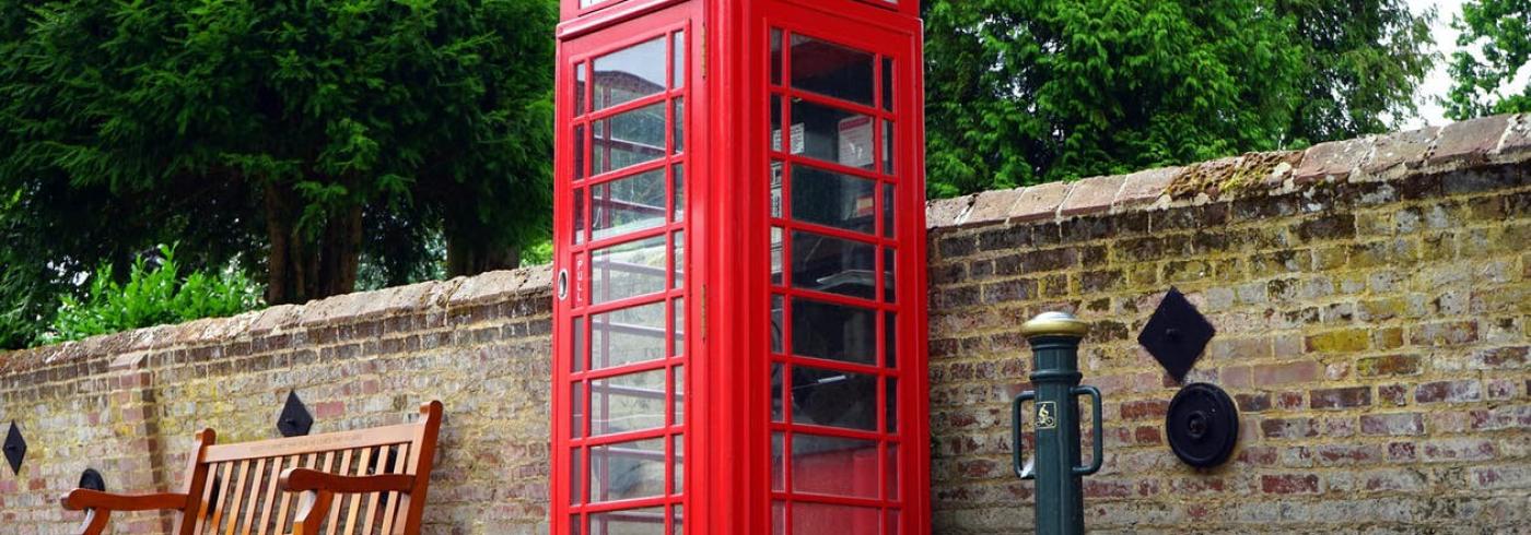 Red phone box next to a stone wall