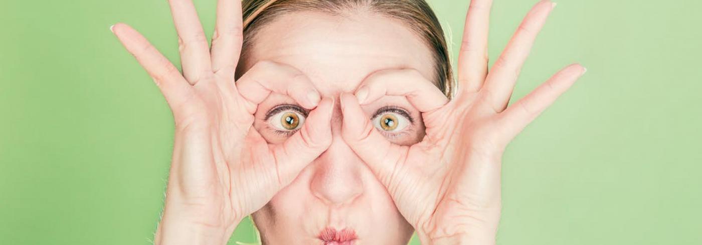 Woman holding her fingers to her eyes to mimic glasses