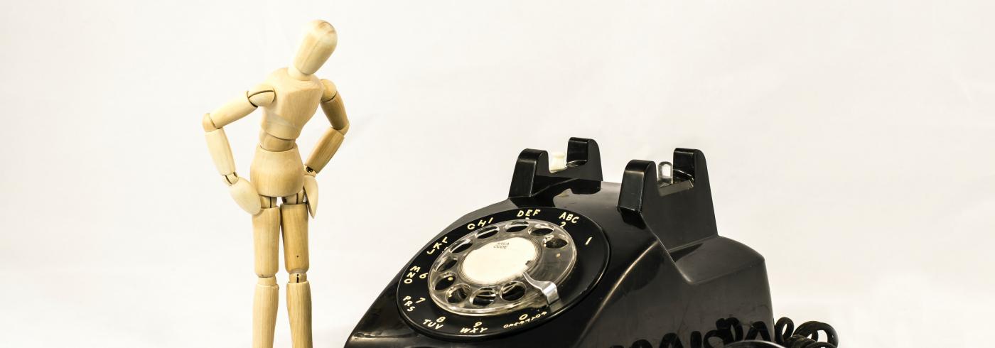 A wooden model next to an old telephone