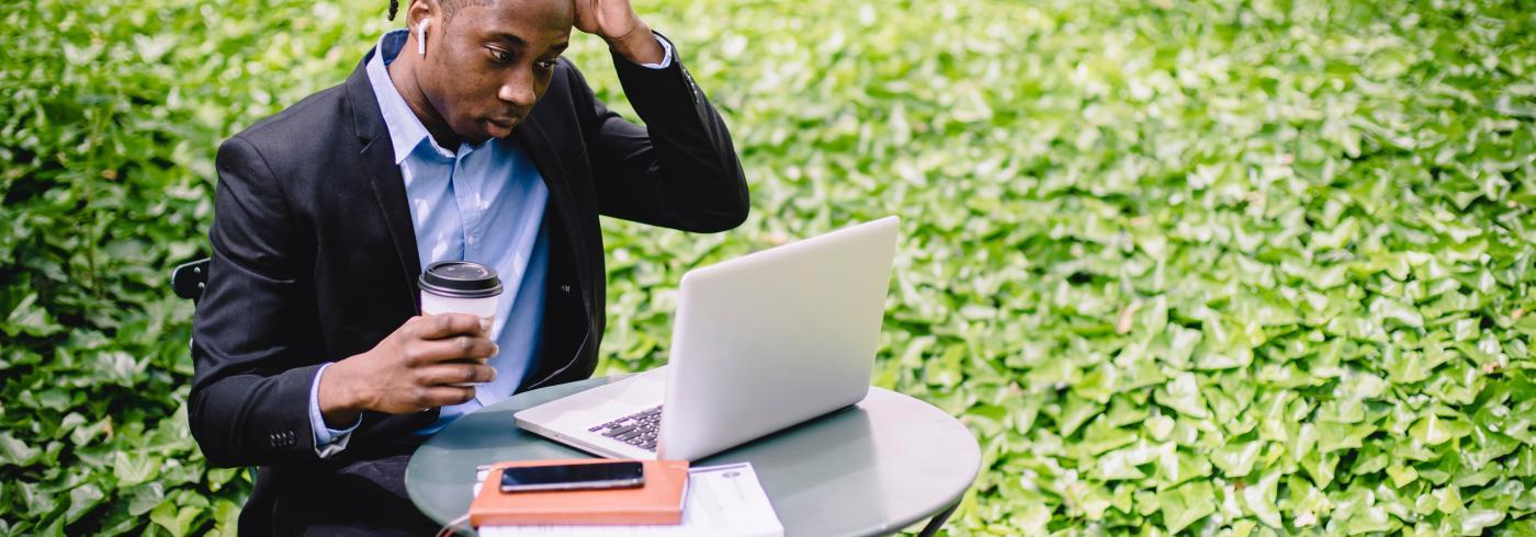 man scratching his head at a laptop