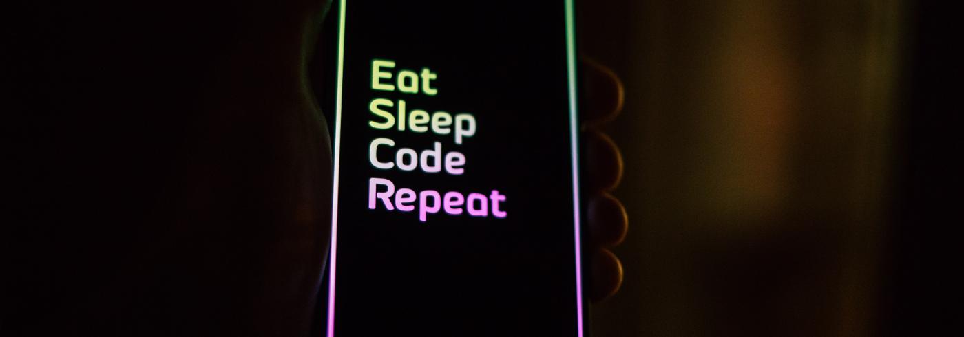 A phone showing the words "eat, sleep, code, repeat"