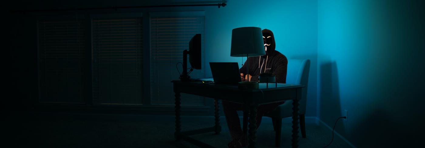 Person with an Anonymous mask using computer