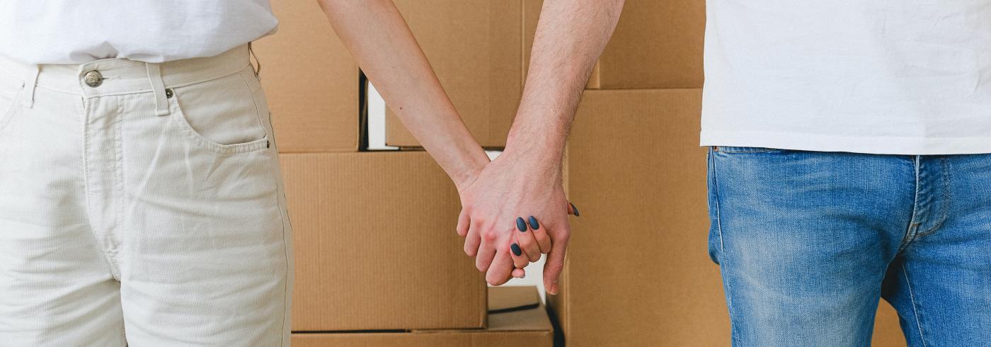 Two people holding hands in front of a stack of boxes