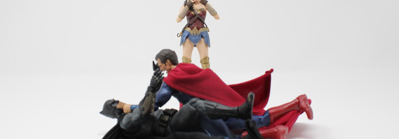 Superman fighting Batman whilst Wonder Woman watches.