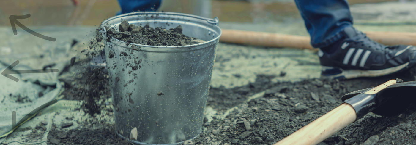 Bucket of dirt with a spade next to it