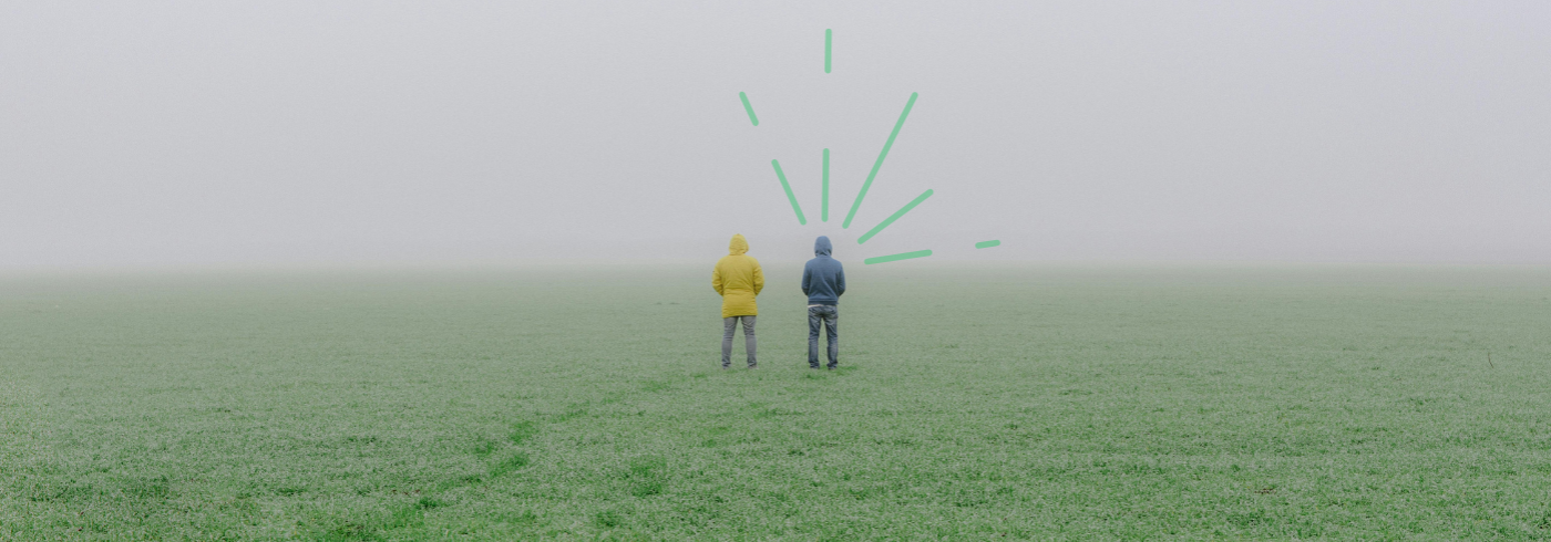 Two men in a field, and a cloudy view ahead of them