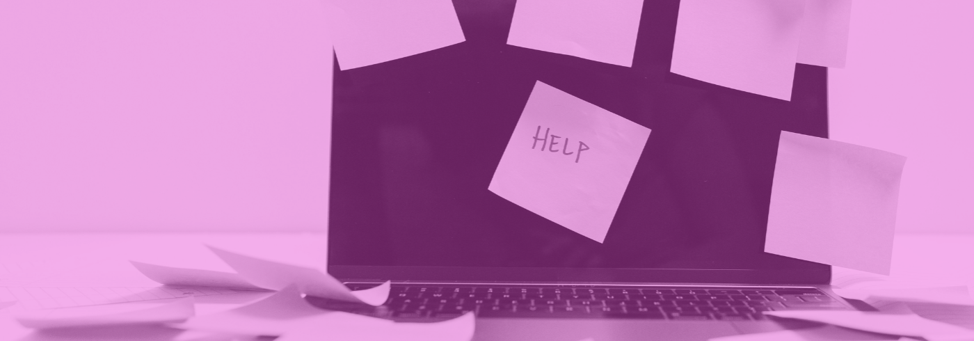 A laptop with a post-it note on the screen saying "Help"